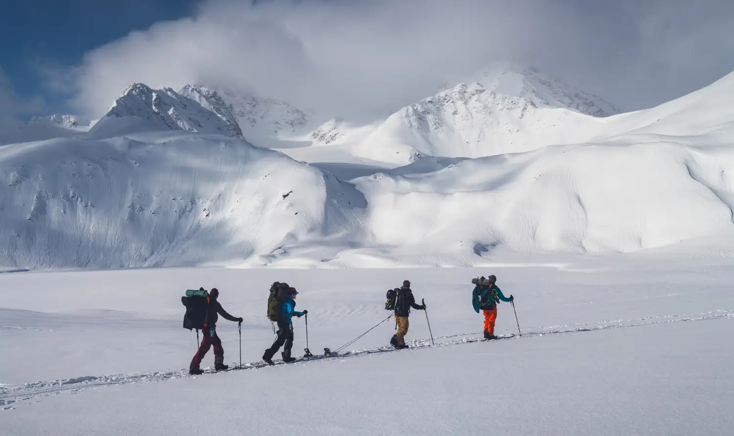 horizontal-shot-group-people-hiking-mountains-covered-snow-cloudy-sky