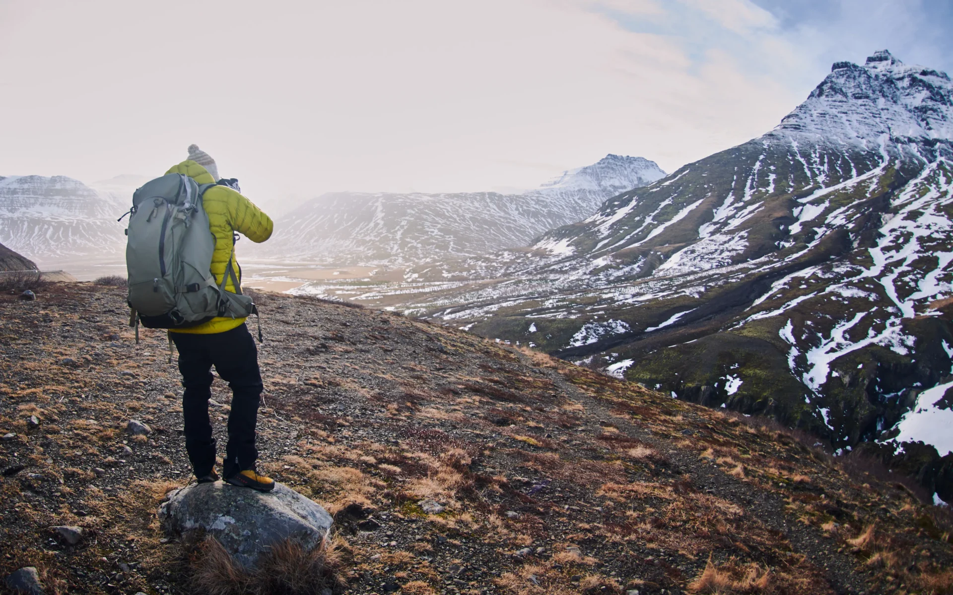 male-hiker-with-backpack-taking-picture-rocky-mountains-covered-snow(2)